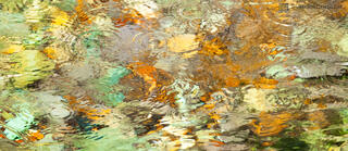Photograph of ripples in a stream of colorful stones