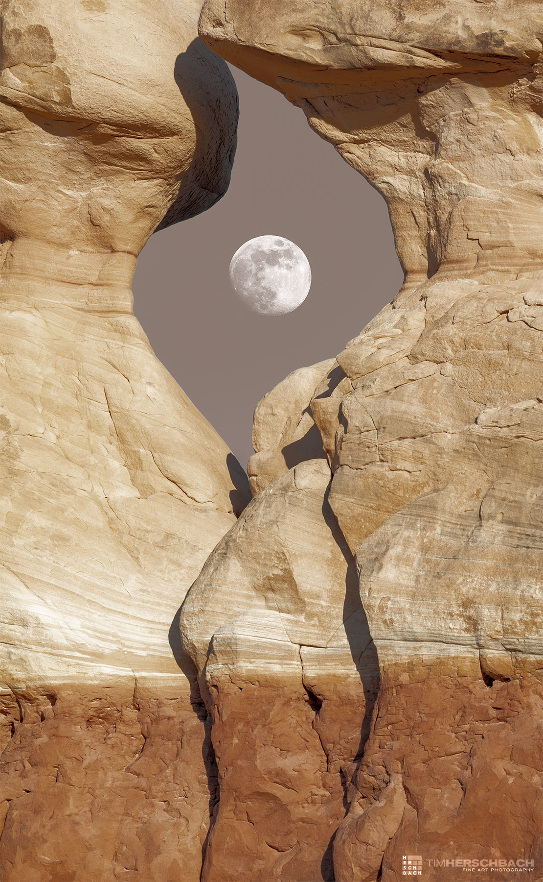Moon rising through a sandstone window in the desert of Utah